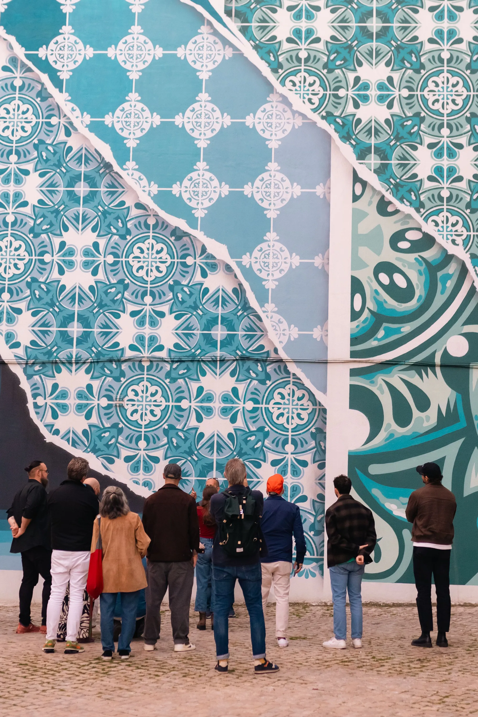 A group standing before a monumental blue-and-white tile mural in Lisbon
