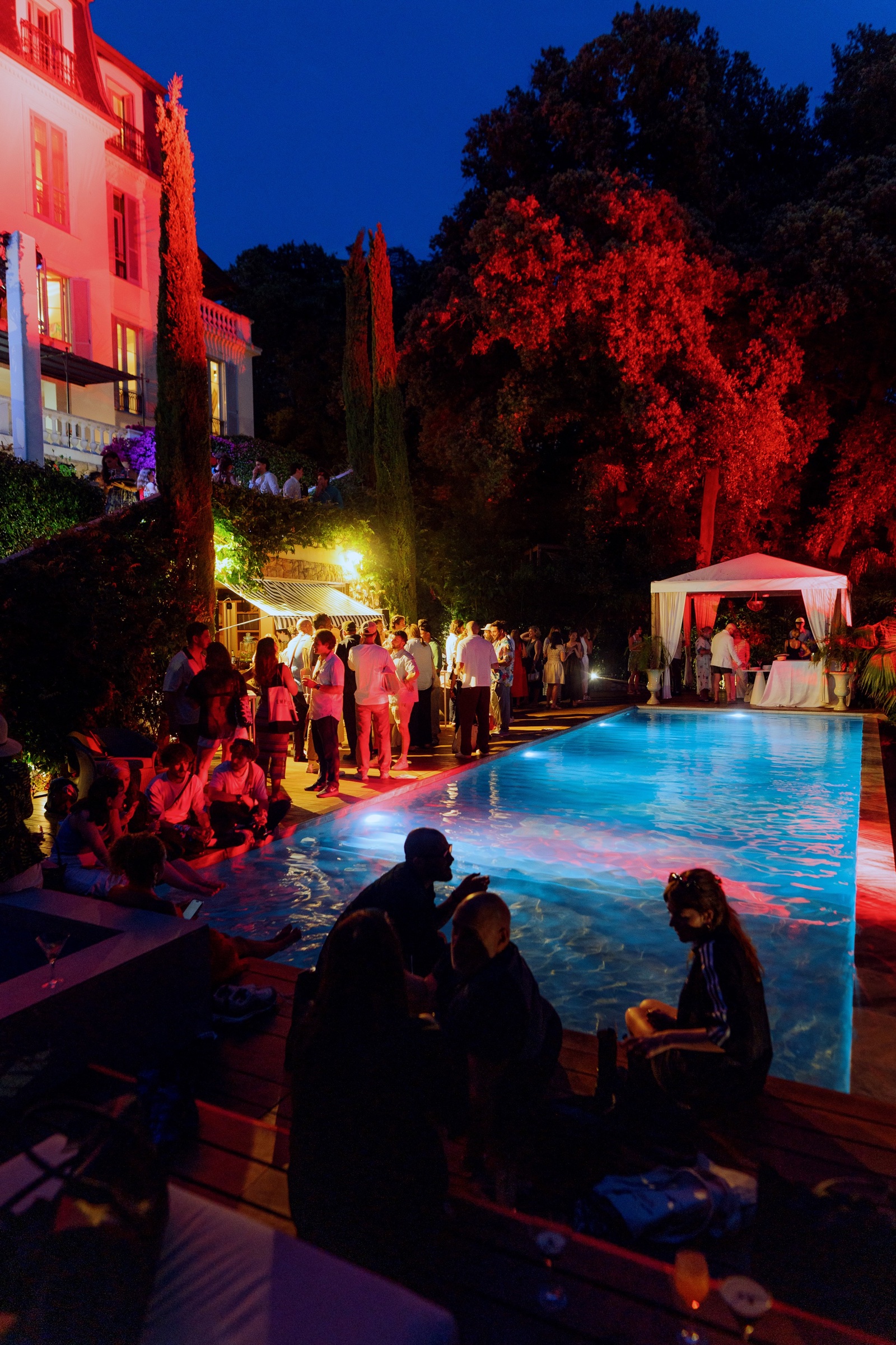 An evening gathering around the illuminated pool