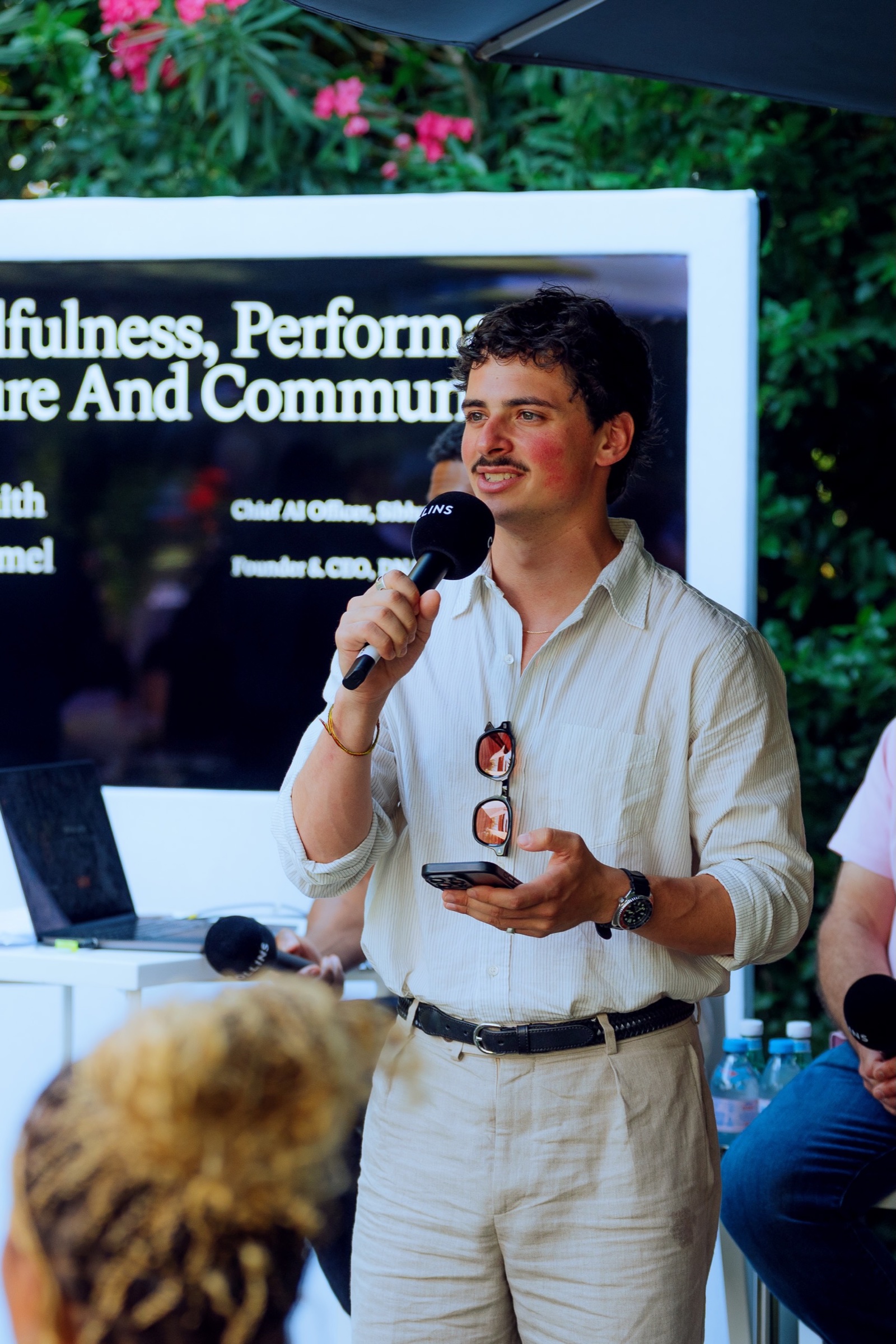 A speaker welcoming guests to a garden conversation