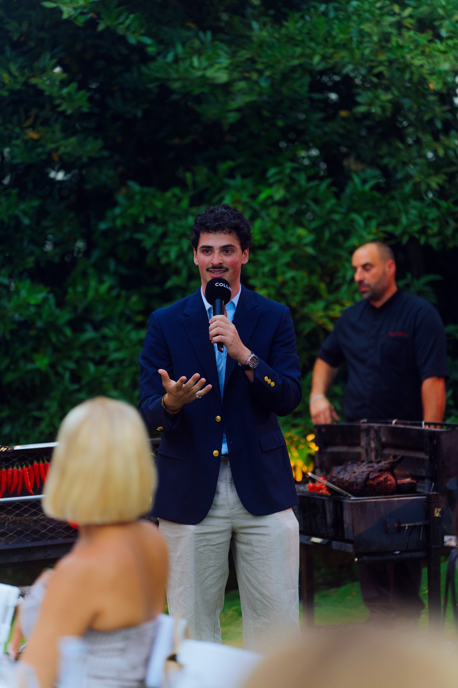 A speaker addressing guests beside the outdoor kitchen
