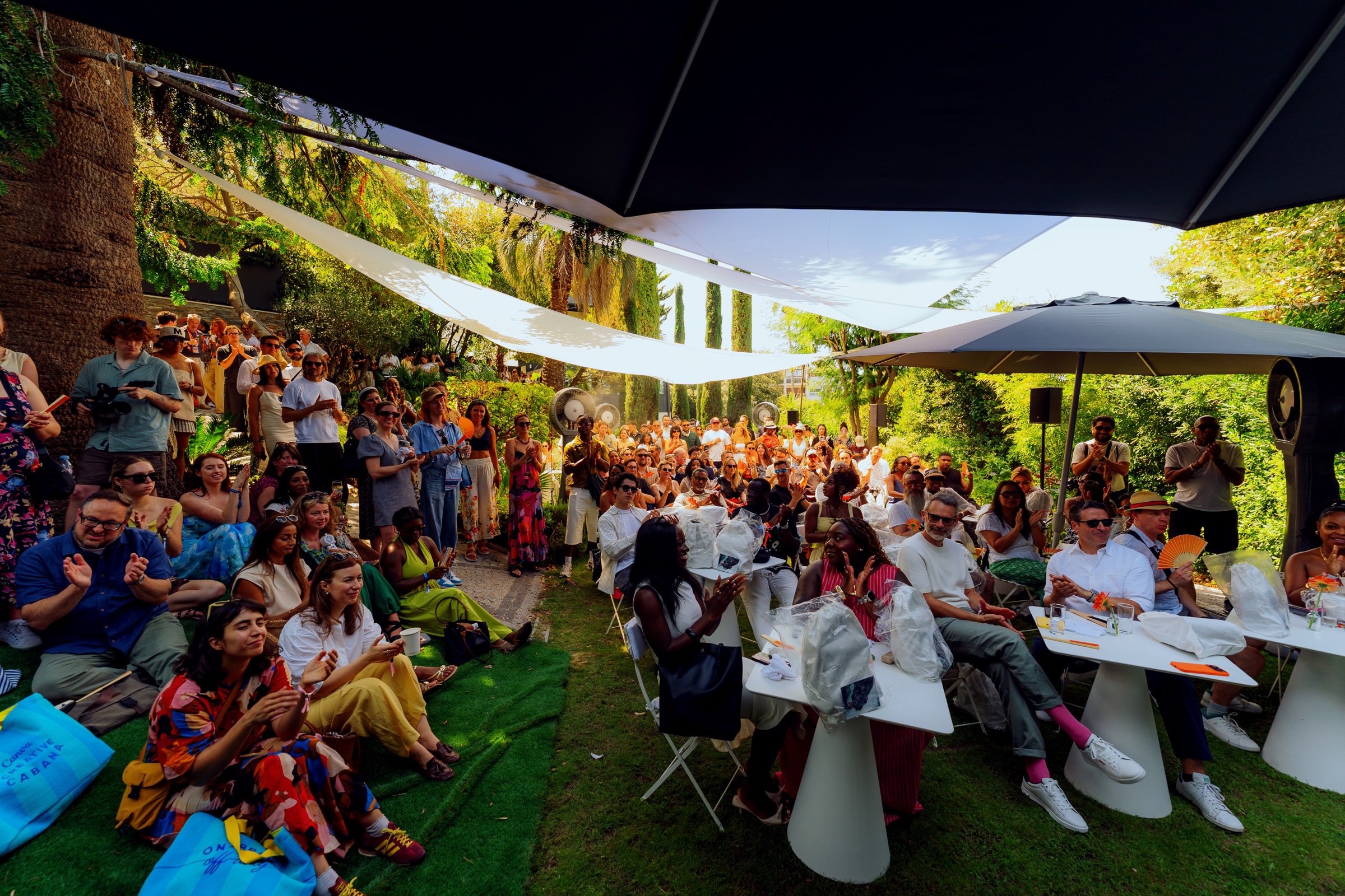 An audience gathered beneath shade sails in the garden