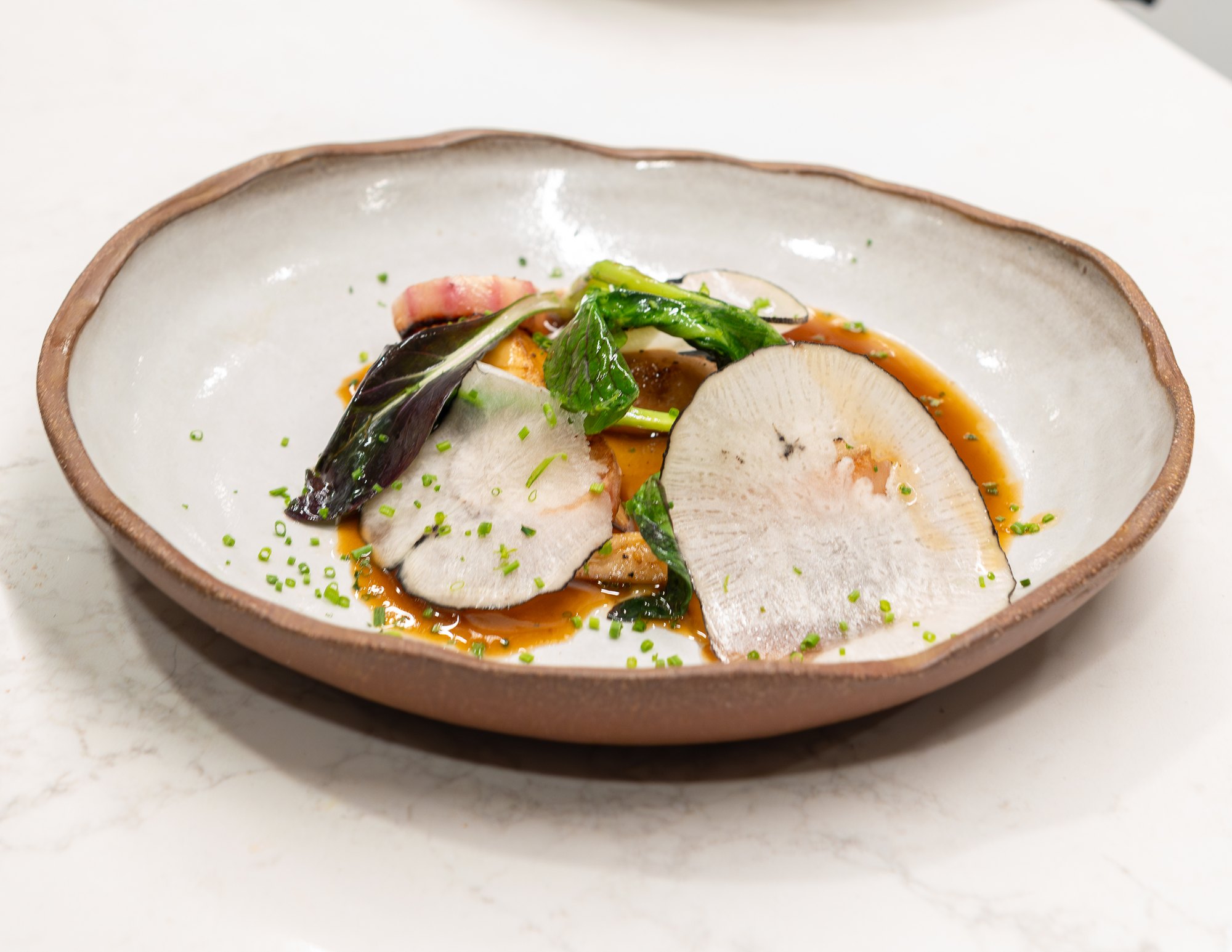 A finished dish with fresh greens and sliced radishes