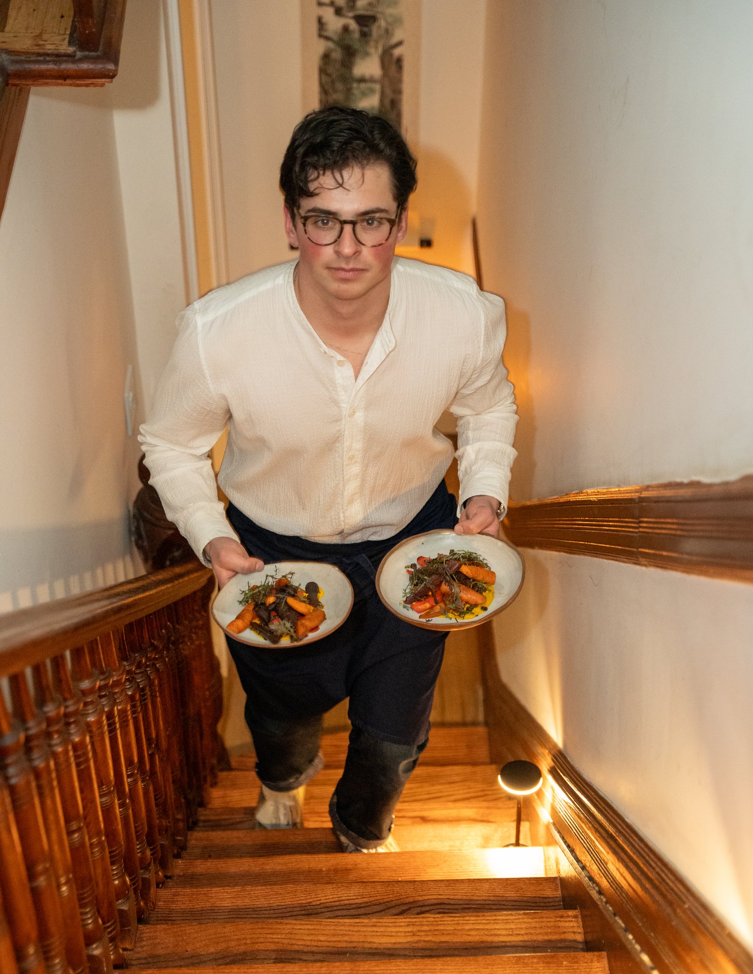 Eron carrying dinner plates up the staircase