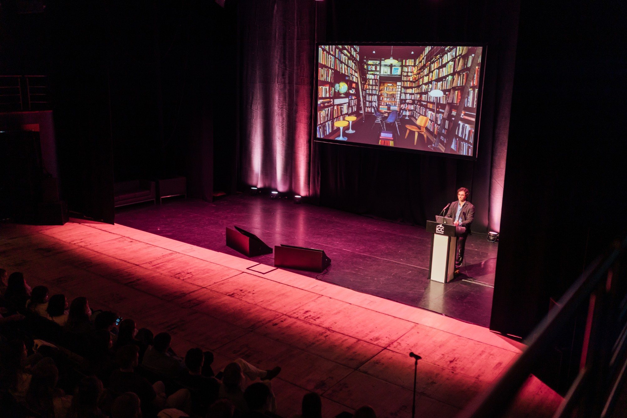 Eron on stage at ICC Belfast in front of a slide of a library