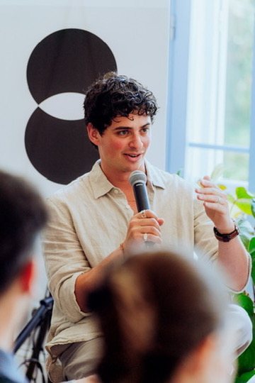 Eron seated with a microphone during a panel