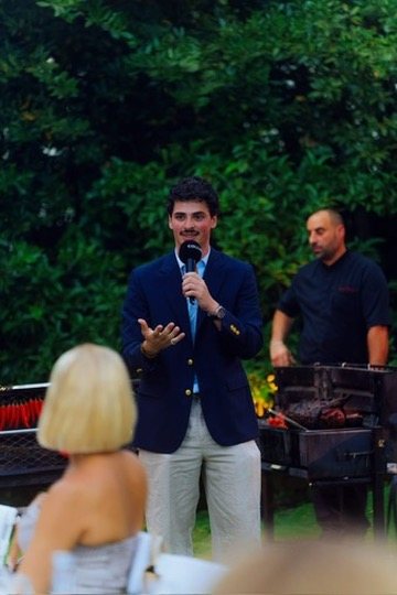 Eron giving a toast at a garden dinner beside the grill