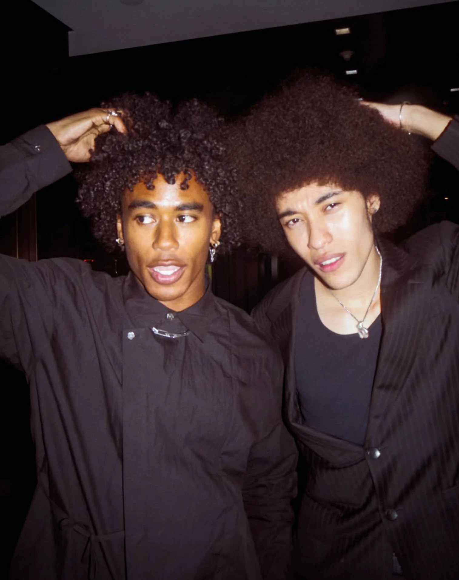 Two guests posing with their hands in their hair
