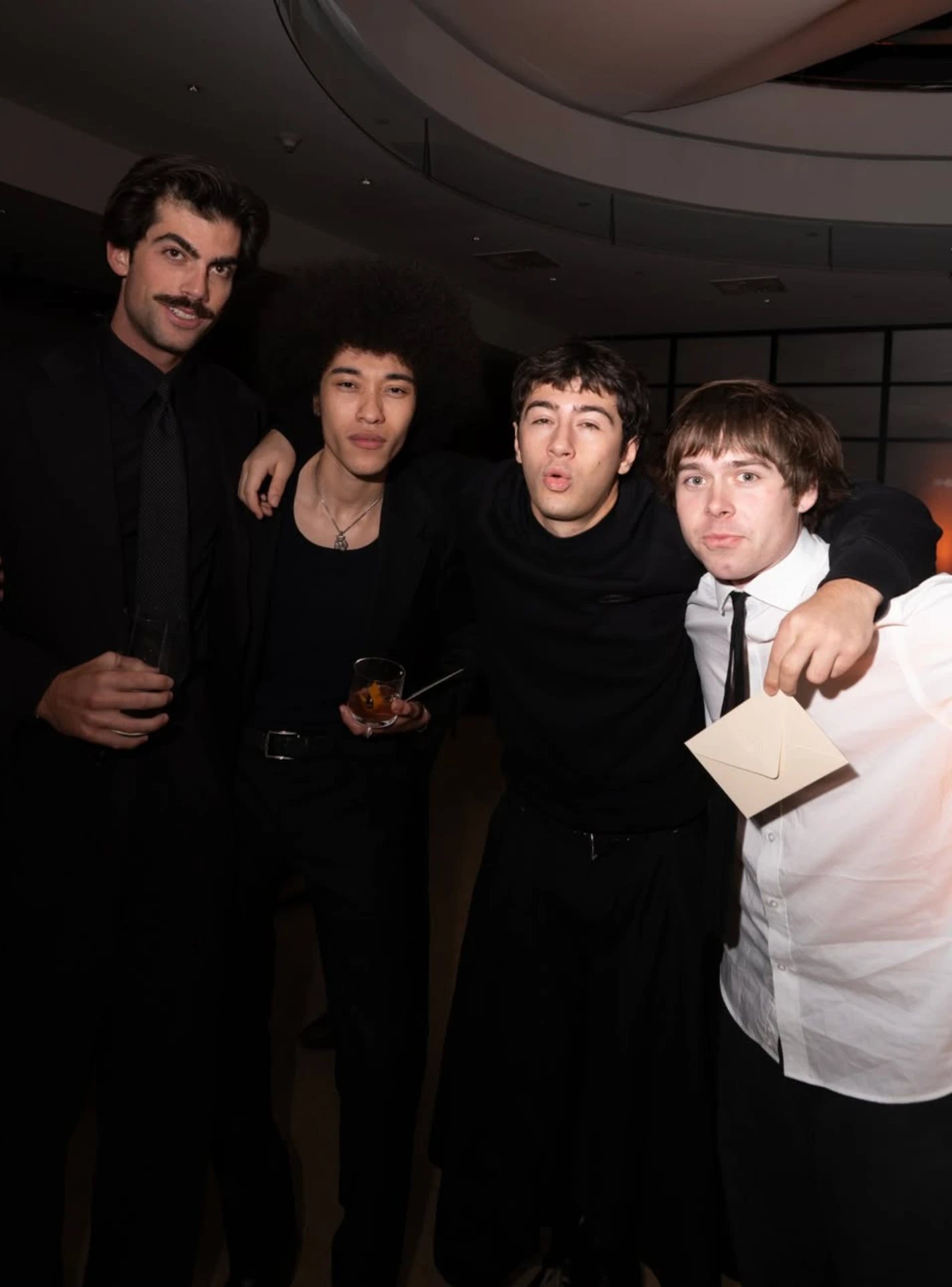 Four guests with their arms around each other, one holding an envelope