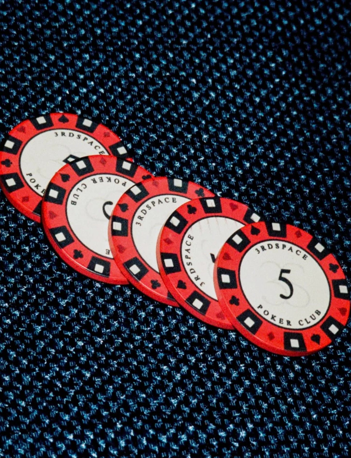 Red 3rd Space Poker Club chips on a blue tablecloth
