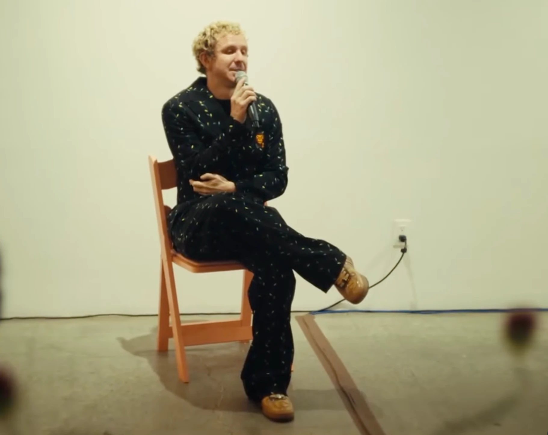 A speaker on a folding chair telling their story with a microphone