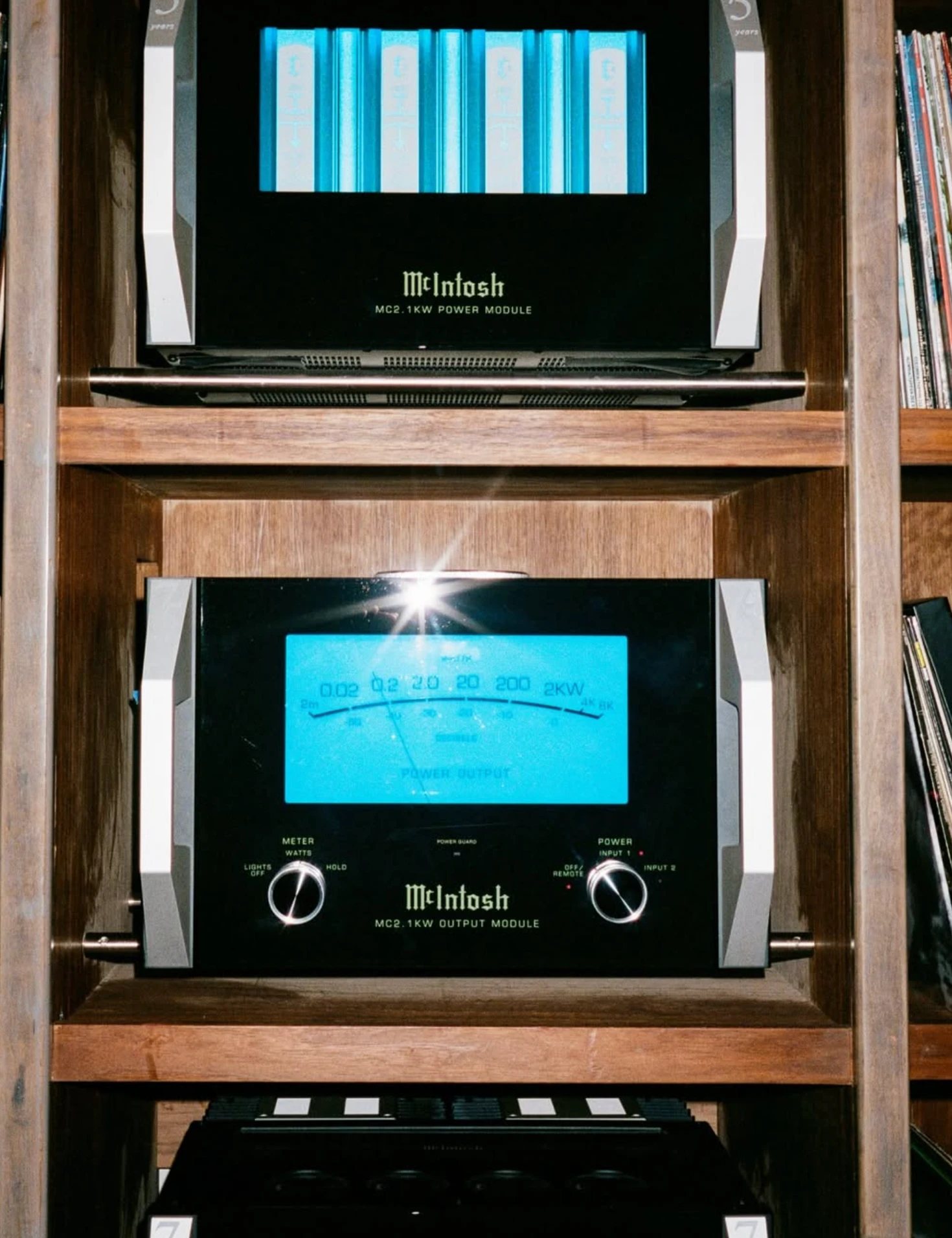 Two McIntosh amplifiers glowing blue on a record shelf